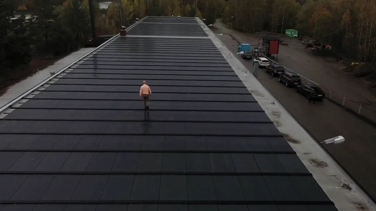 Instalator idzie po ultralekkim panelu fotowoltaicznym FaradayX zamontowanym na dachu